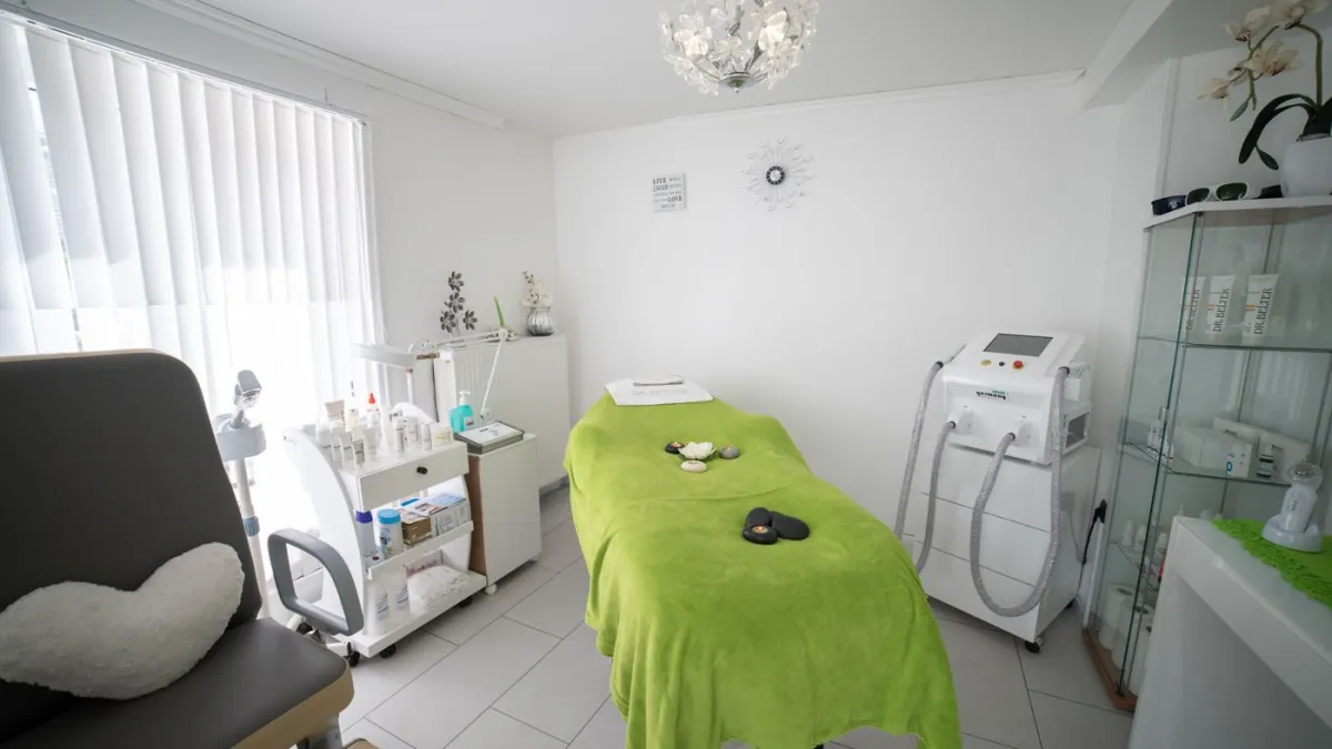 Empty wellness treatment room with a massage bed and equipment.