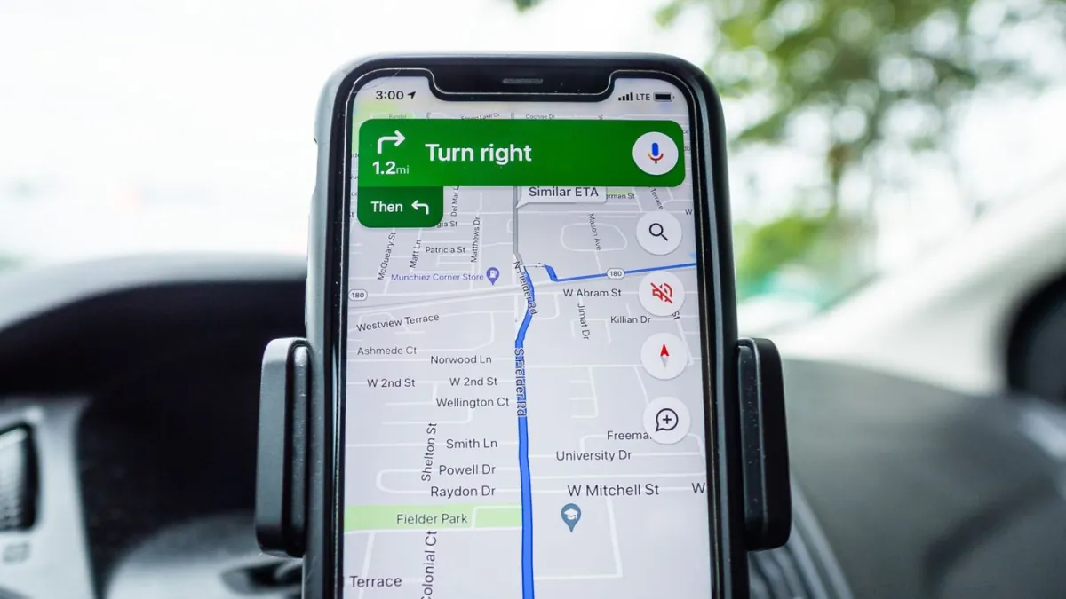 Phone mounted in a vehicle showing turn-by-turn directions.