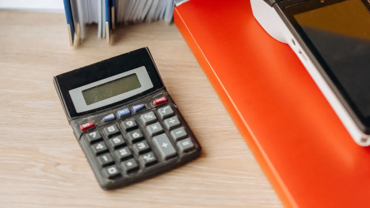 Calculator beside loan paperwork and folders on a desk.