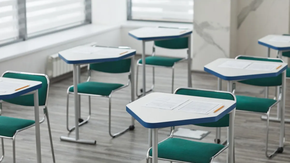 Empty classroom desks prepared with exam papers and pencils.