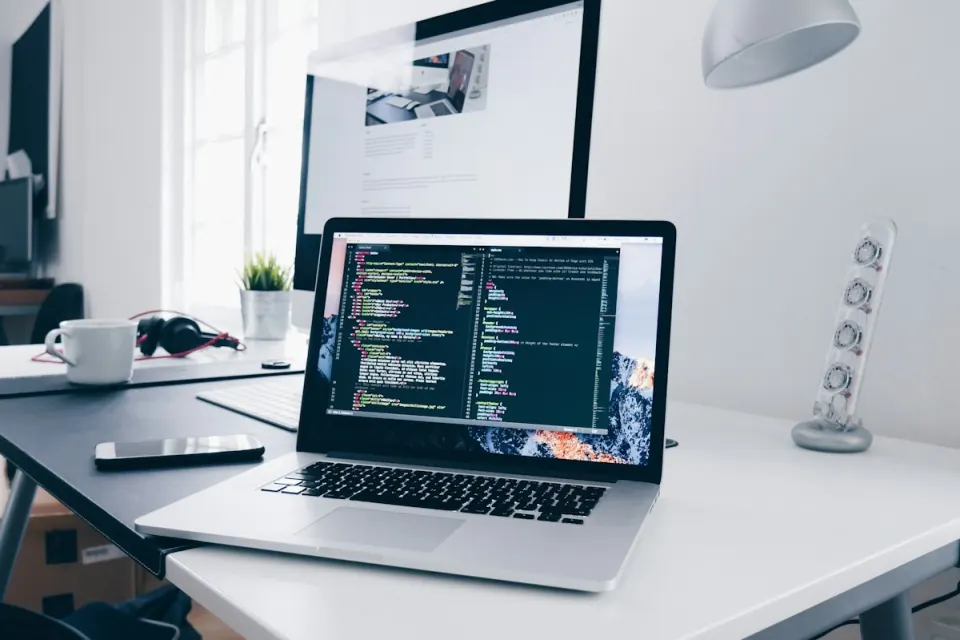 Laptop and desktop monitor on a software development desk